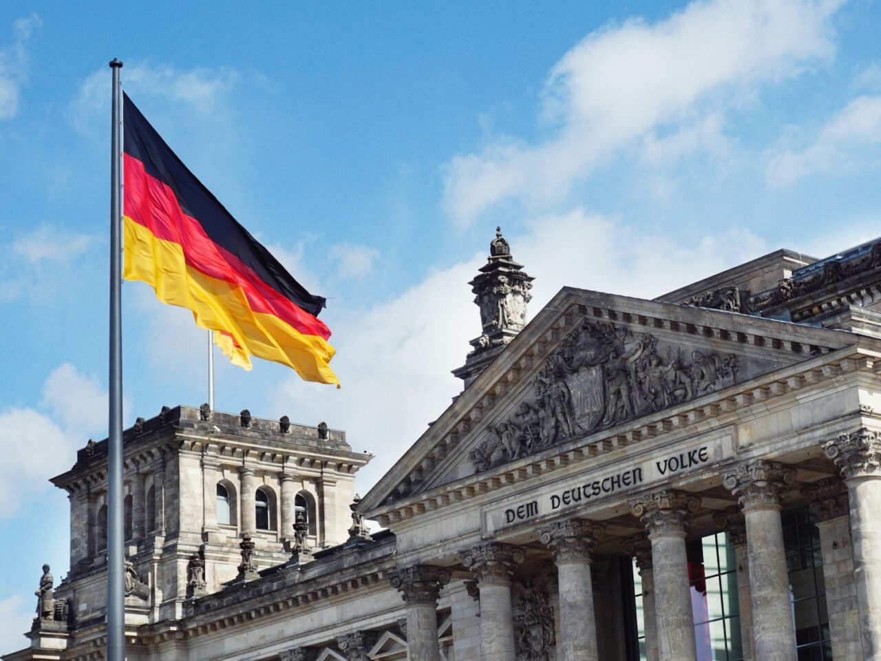 white concrete building with flags on top under blue sky during daytime