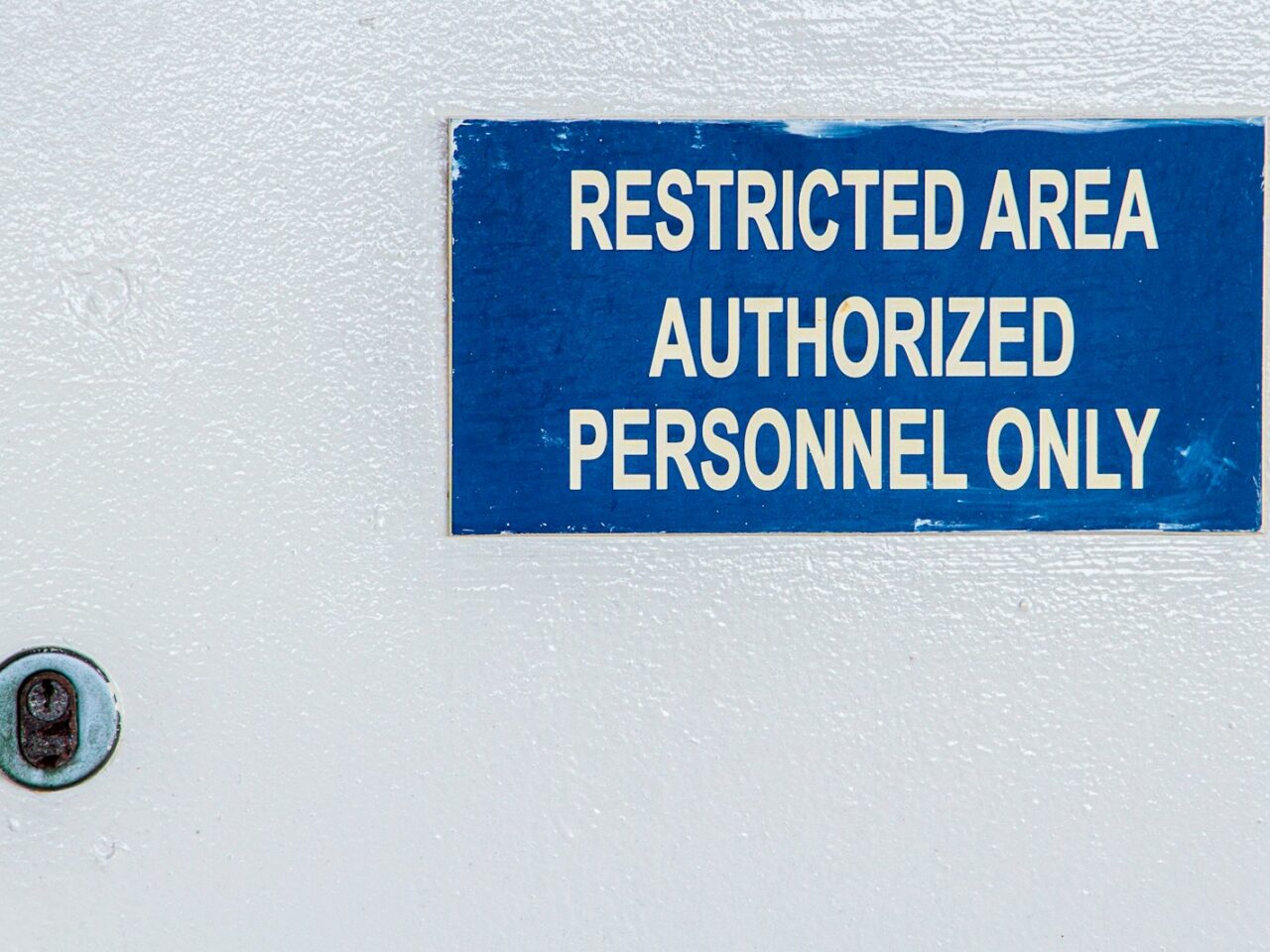 a blue sign on a white wall stating restricted area authorized personnel only