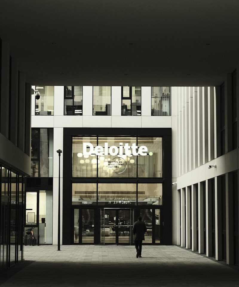 Man walks towards deloitte building entrance.